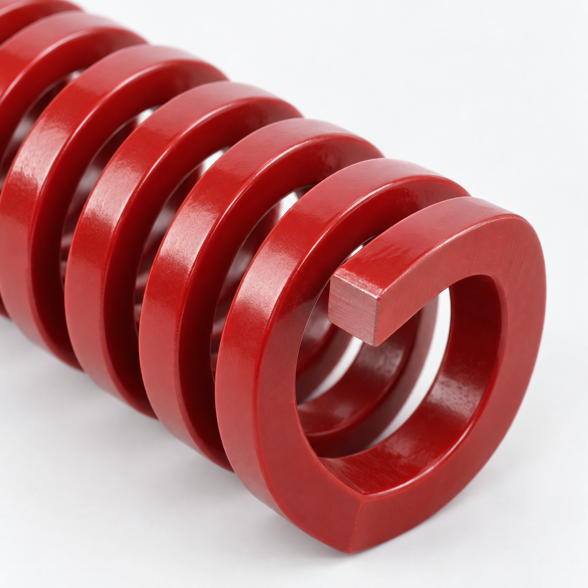 Close-up of red rectangular-wire die spring coating and ground end